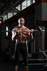Fototapeta na wymiar Mature Bodybuilder Exercising Biceps With Barbell