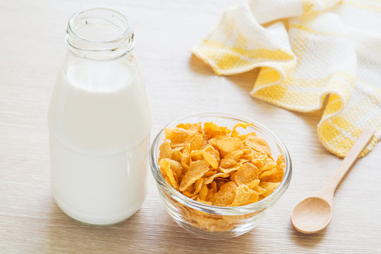Bowl of cornflake and milk bottle on table