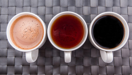 Hot beverages of chocolate, tea and black coffee on woven place 