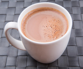 A mug of hot chocolate on a woven place mat.