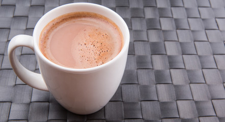 A mug of hot chocolate on a woven place mat.
