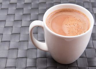 A mug of hot chocolate on a woven place mat.