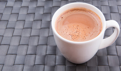 A mug of hot chocolate on a woven place mat.