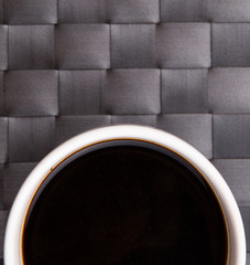 A mug of black coffee on a woven place mat