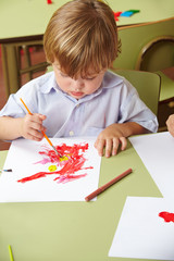 Kind malt im Kindergarten mit Pinsel
