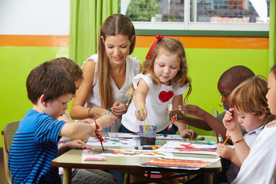 Kinder malen mit Erzieher im Kindergarten
