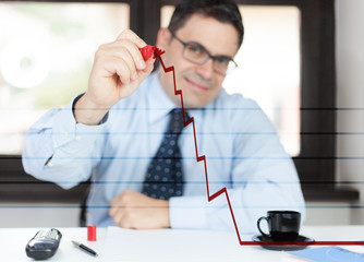Uomo in ufficio disegna un grafico in salita © Danilo Rizzuti