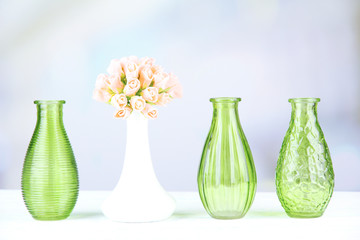 Different decorative vases on shelf on light background