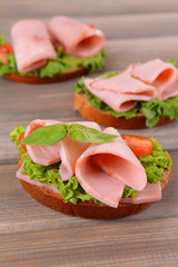 Delicious sandwiches with lettuce and ham on table close-up