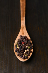 Spice pepper in spoon on wooden background