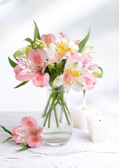 Alstroemeria flowers in vase on table on light background