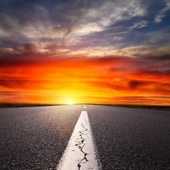 Fototapeta na wymiar Jazdy na pustej drodze asfaltowej o zachodzie słońca