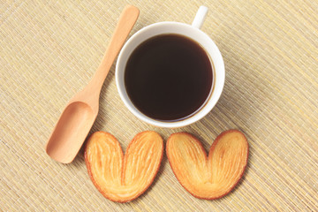 Cup of coffee and cookies in the form of heart on rice straw bac