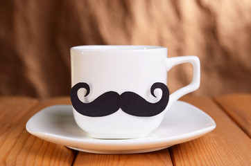 Cup with mustache on table on brown background