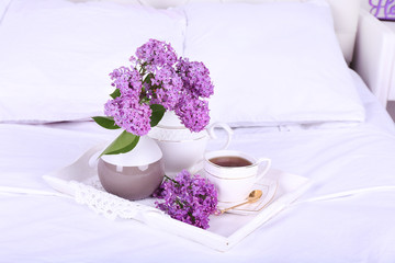 Wooden tray with light breakfast on bed