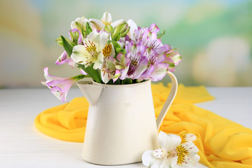Bouquet of freesias in pitcher on table on natural background