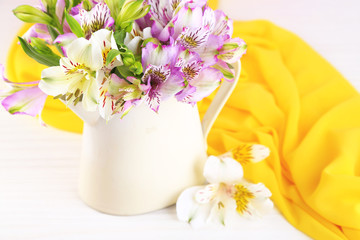 Bouquet of freesias in pitcher on table close-up