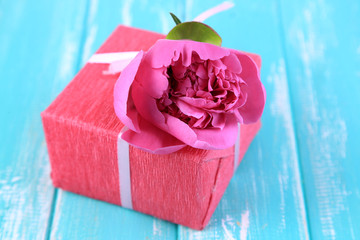 Pink gift with bow and flower on wooden table close-up