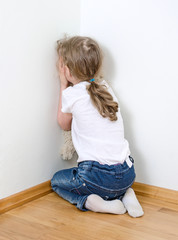 Fototapeta premium Little girl crying in the corner. Domestic violence concept.