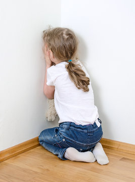 Little girl crying in the corner. Domestic violence concept.