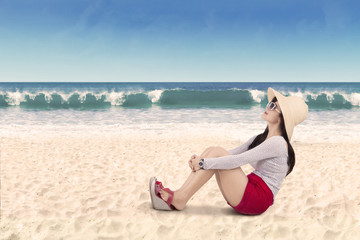 Woman sitting on the white beach sand