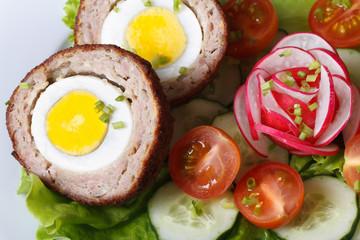 Scotch egg on a salad of tomatoes, cucumbers and radishes