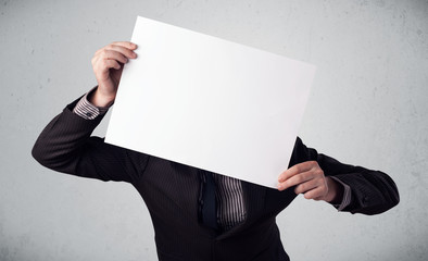 Businessman holding in front of his head a paper with copy space