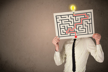 Businessman holding a paper with a labyrinth on it in front of h