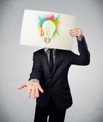 Businessman holding a cardboard with paint splashes and lightbul