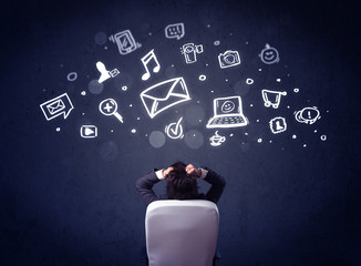 Businessman in chair with multimedia icons over his head