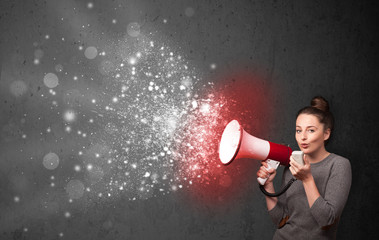 Woman shouting into megaphone and glowing energy particles explo