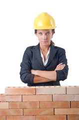 Young female builder near brick wall