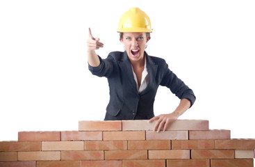 Young female builder near brick wall