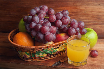 glass of juice and fruit in a wicker basket
