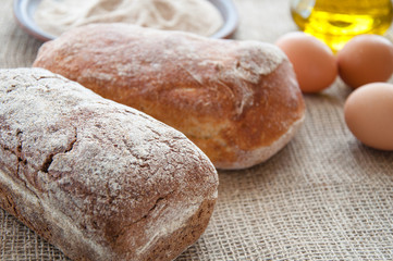 Homemade bread ciabatta on the table. Olive oil, eggs and flour