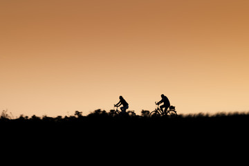 Fototapeta na wymiar Silhouette of two riding bikers on sunset.