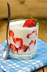 Yogurt thick with strawberries and spoon on board