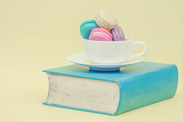 Sweet and colourful french macaroons in cup on book. retro-vinta