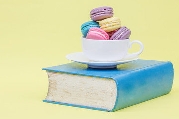 Sweet and colourful french macaroons in cup on book. retro-vinta