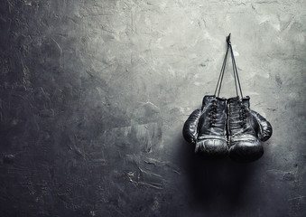 old boxing gloves hang on nail on texture wall - obrazy, fototapety, plakaty