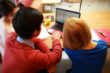 Back view portrait of a young friends using laptop together
