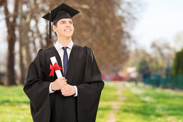 Proud college graduate holding diploma in park