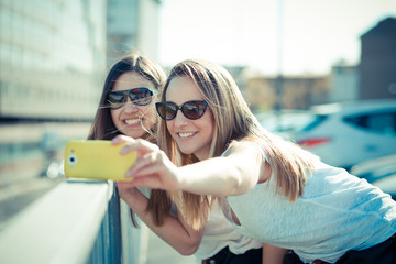 two beautiful young women using smart phone selfie
