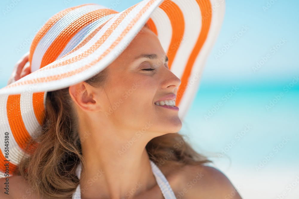 Poster portrait of relaxed young woman in hat on beach