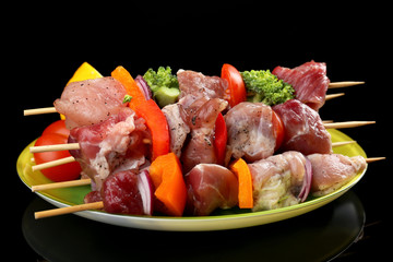 Raw pork kebab on black background