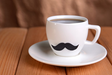 Cup with mustache on table on brown background