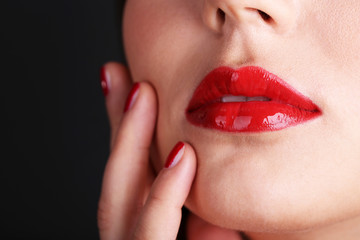 Girl with red lips and nails on dark background