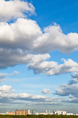 urban houses under big white clouds in blue sky