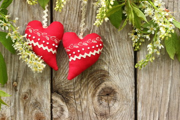 Czerwone serca na drewnianym tle wśród kwiatów