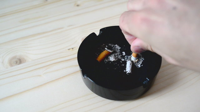 Hand putting out cigarette in ashtray on the table. 1920x1080